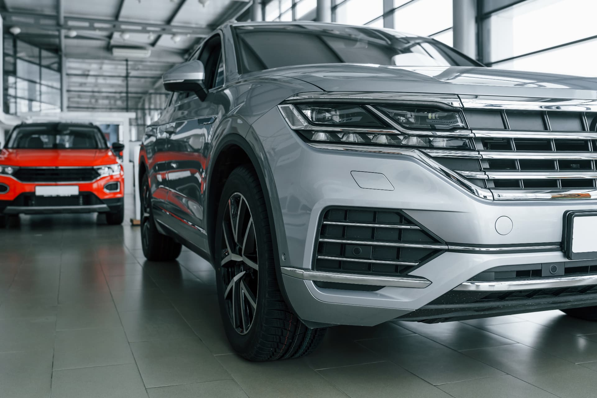 Front view of a modern silver car in a brightly lit dealership showroom